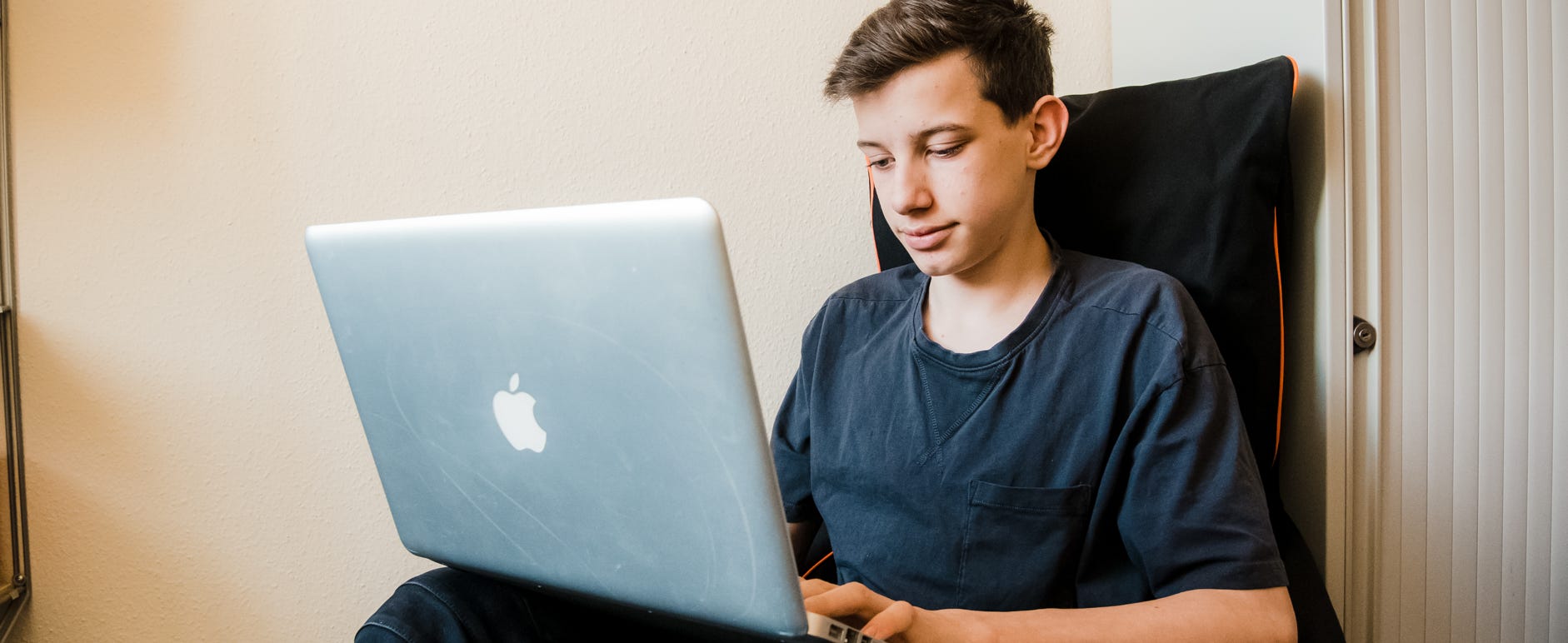 Junge mit Laptop beim Online lernen